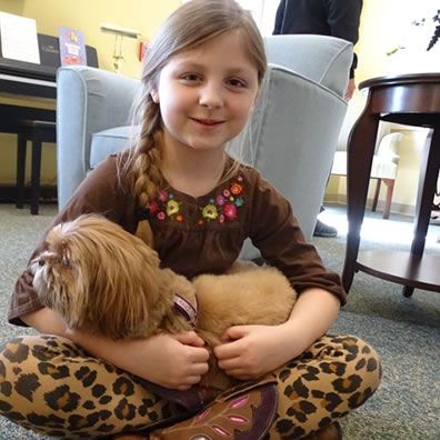 A little girl is sitting on the floor holding a dog