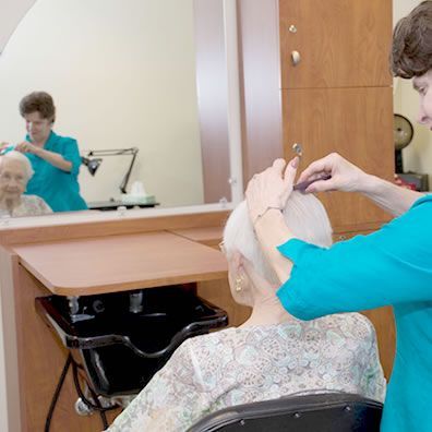 A woman is cutting a woman 's hair in front of a mirror.