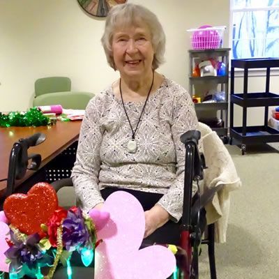 A woman in a wheelchair is holding a pink heart