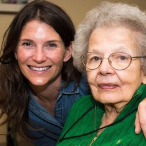 Two women are posing for a picture together and one is wearing glasses.