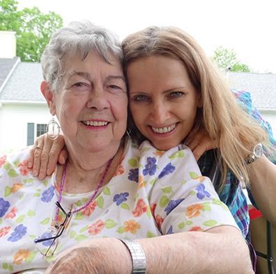 Two women are posing for a picture together and smiling for the camera.