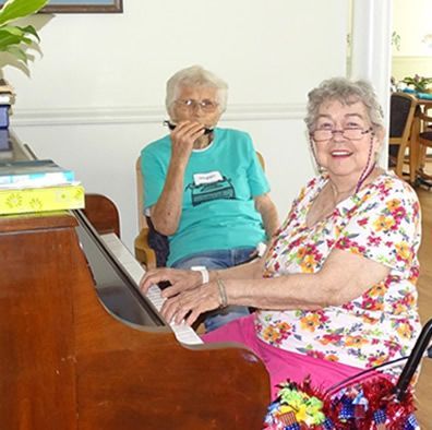 A woman in a floral shirt is playing a piano