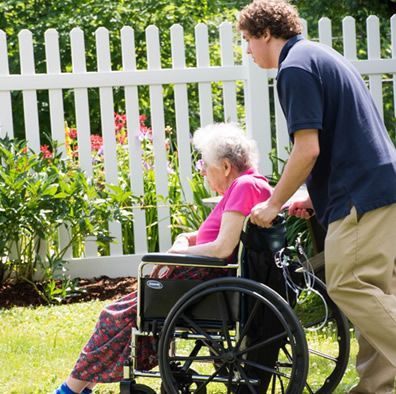 A man pushes an older woman in a wheelchair