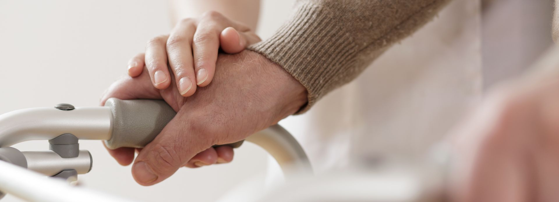 A woman is holding a man 's hand while using a walker.