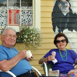 A man and woman are eating ice cream in front of a dalmatian dog mural