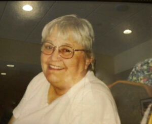 A woman wearing glasses and a white shirt is smiling