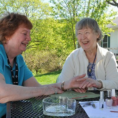 Two older women are sitting at a table laughing