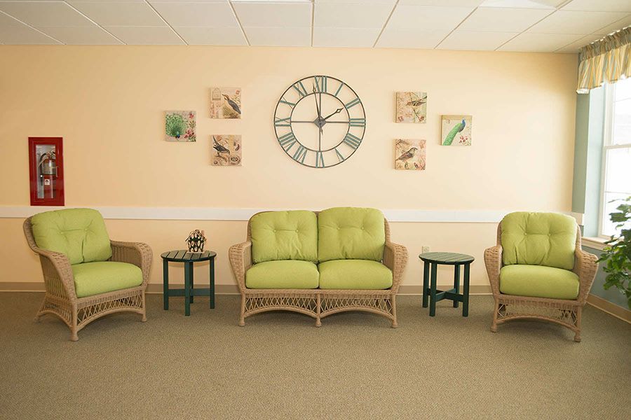 A living room with green furniture and a clock on the wall