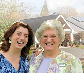 Two women posing for a picture in front of a house