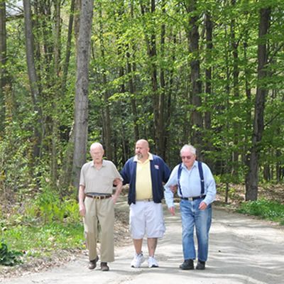 Three men are walking down a dirt road in the woods