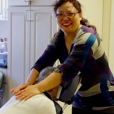 A woman is smiling while giving a man a massage