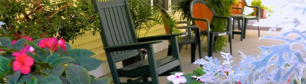 A patio with a table and chairs and flowers in the foreground.