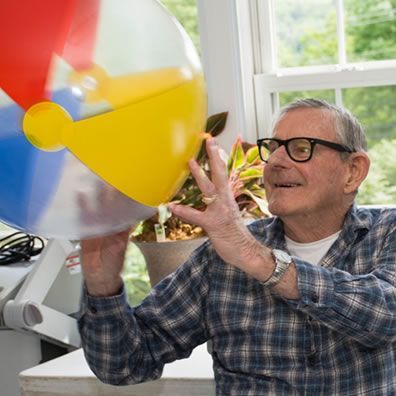 A man wearing glasses is playing with a beach ball