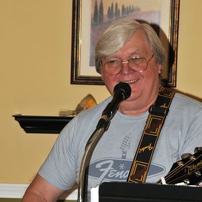 A man wearing a fender shirt is singing into a microphone