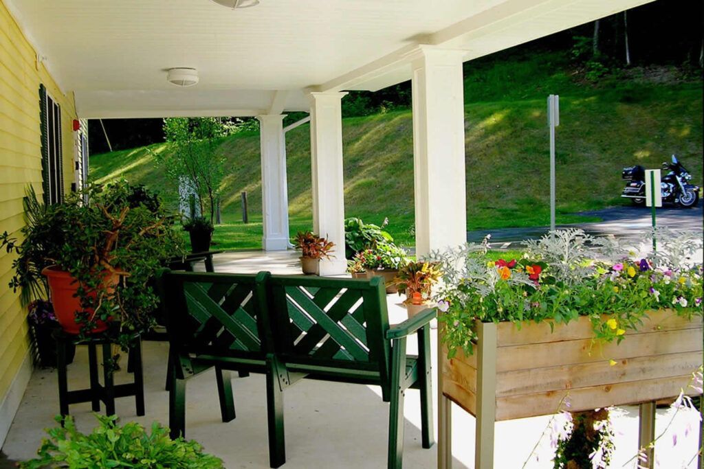 A porch with a green bench and potted plants