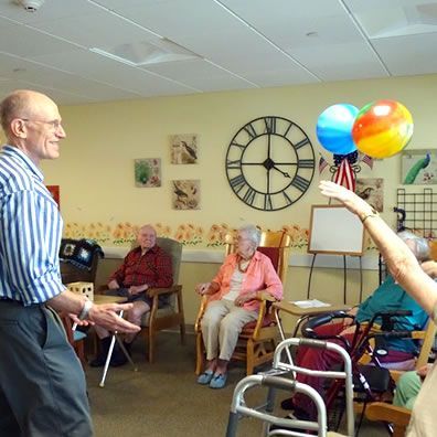 A man in a striped shirt is standing in front of a group of elderly people