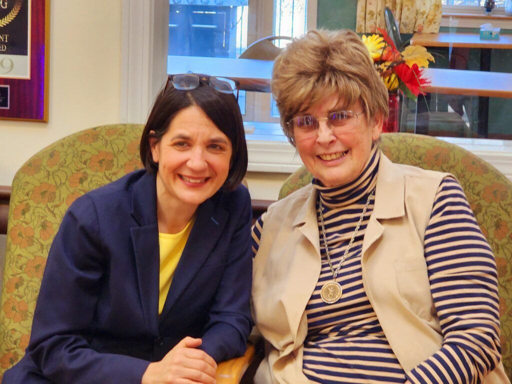 Two women are posing for a picture and one is wearing glasses
