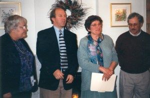 A group of people standing in a room with a wreath on the wall behind them