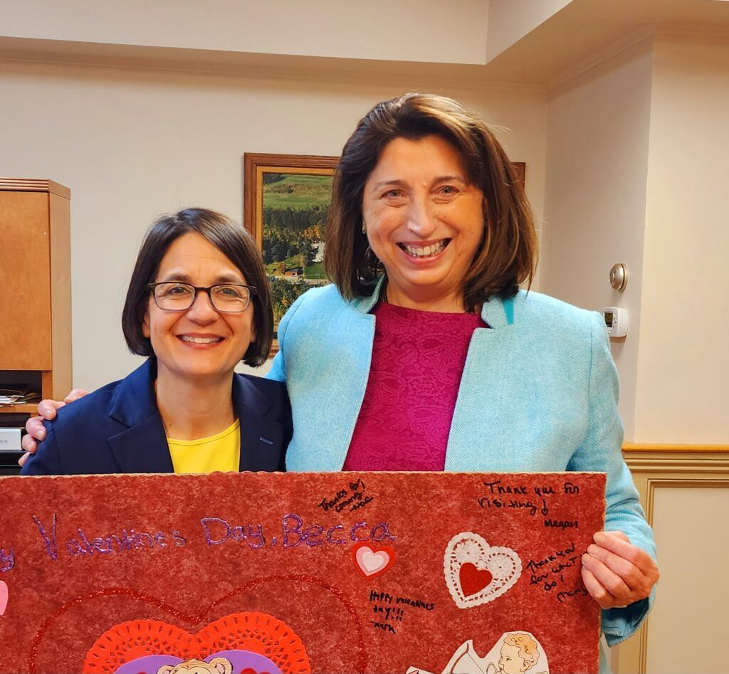 Two women are posing for a picture while holding a sign that says