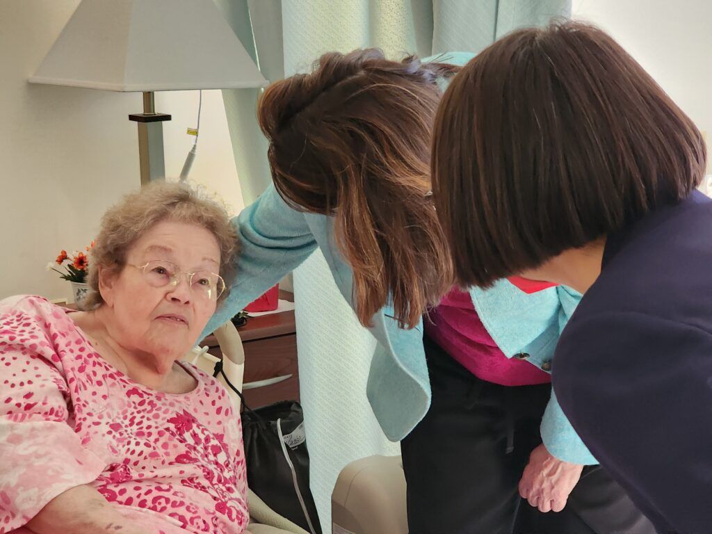 Two women are talking to an elderly woman in a chair