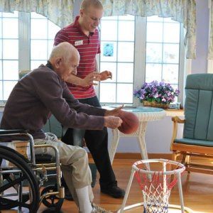 A man in a wheelchair is playing basketball with another man