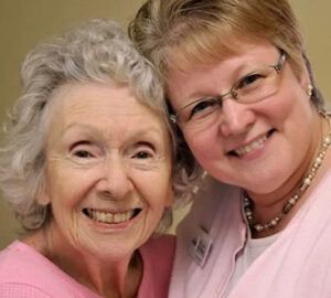 Two women are posing for a picture together and smiling for the camera.