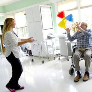 A woman is dancing next to a man in a wheelchair