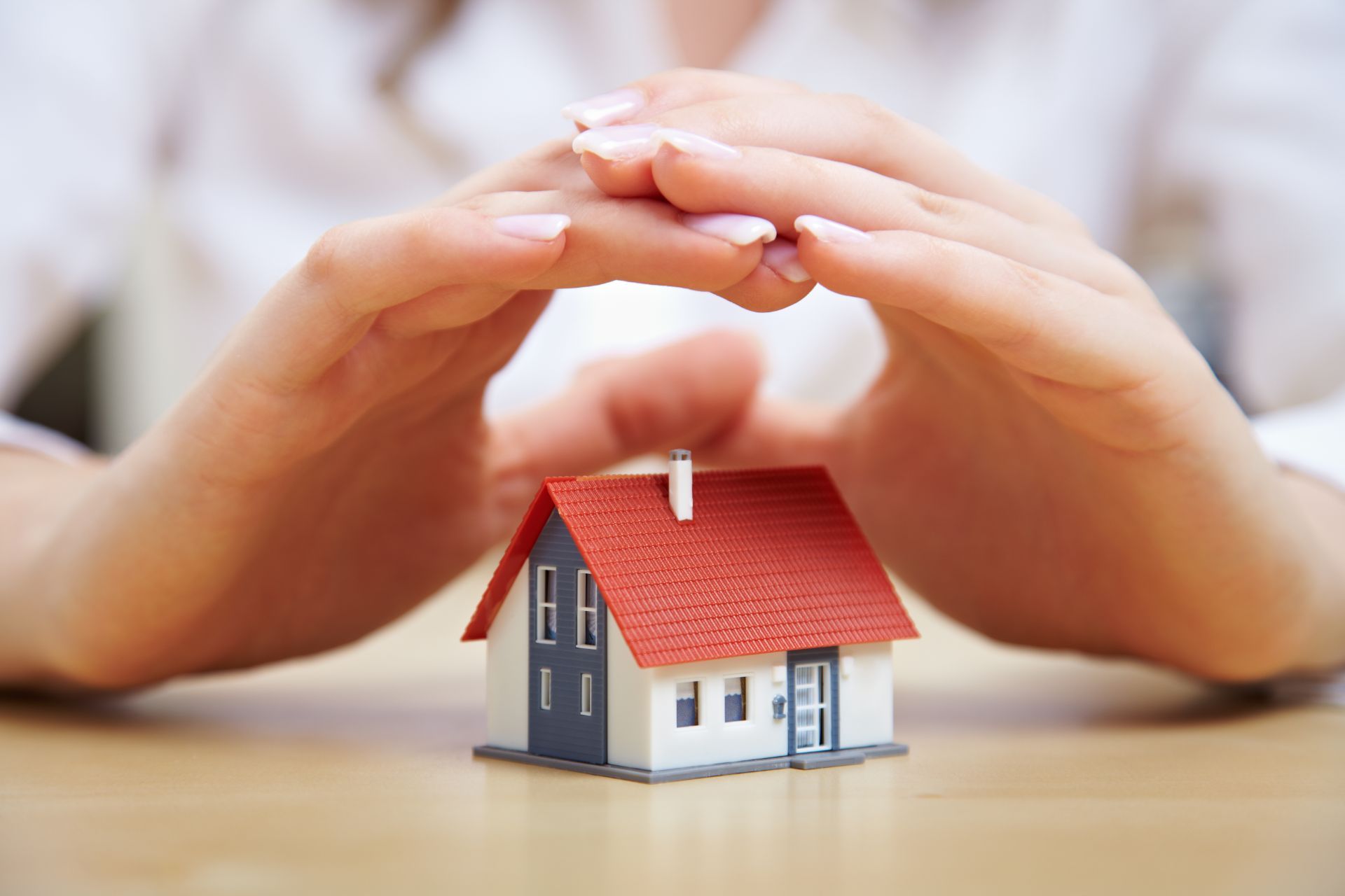 Hands shielding a miniature house