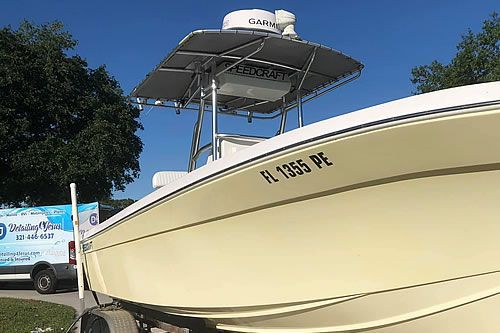 Yellow boat with a white canopy and navigation equipment, parked on a trailer.