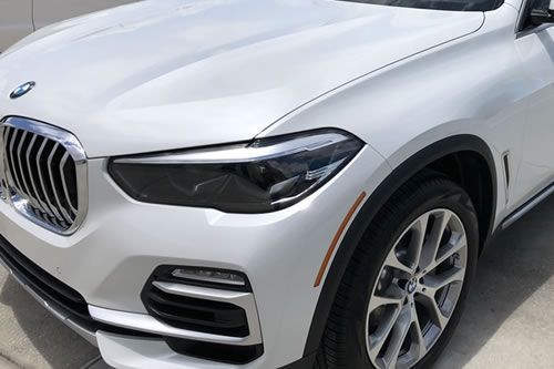 White BMW X5 SUV, front view. Chrome grille and headlight details visible.