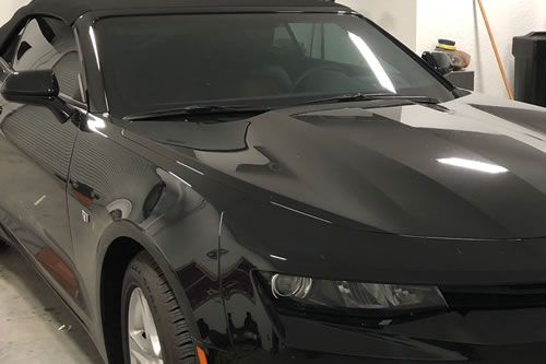 Black convertible car indoors, top down.