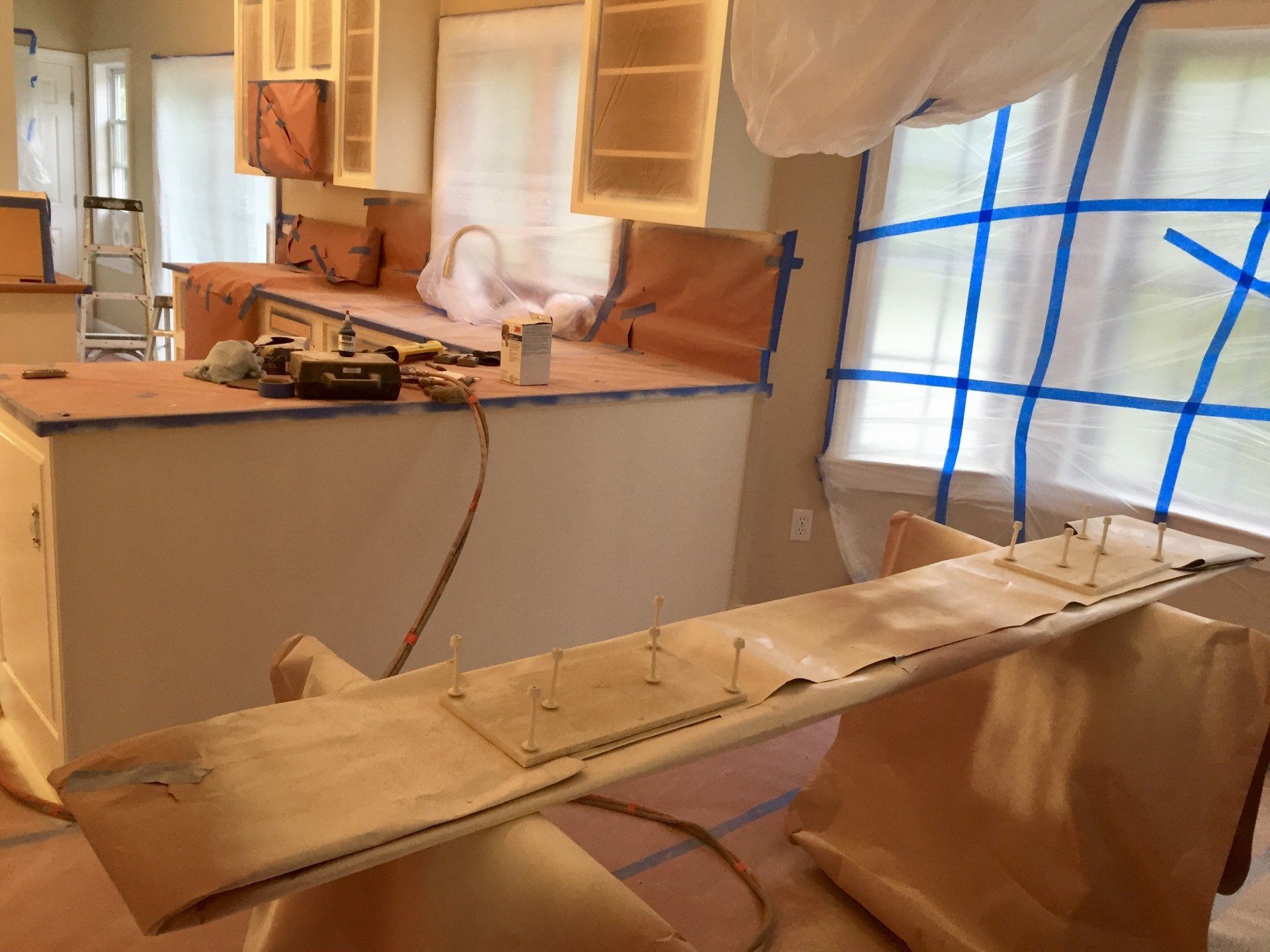 A kitchen under construction with blue tape on the windows