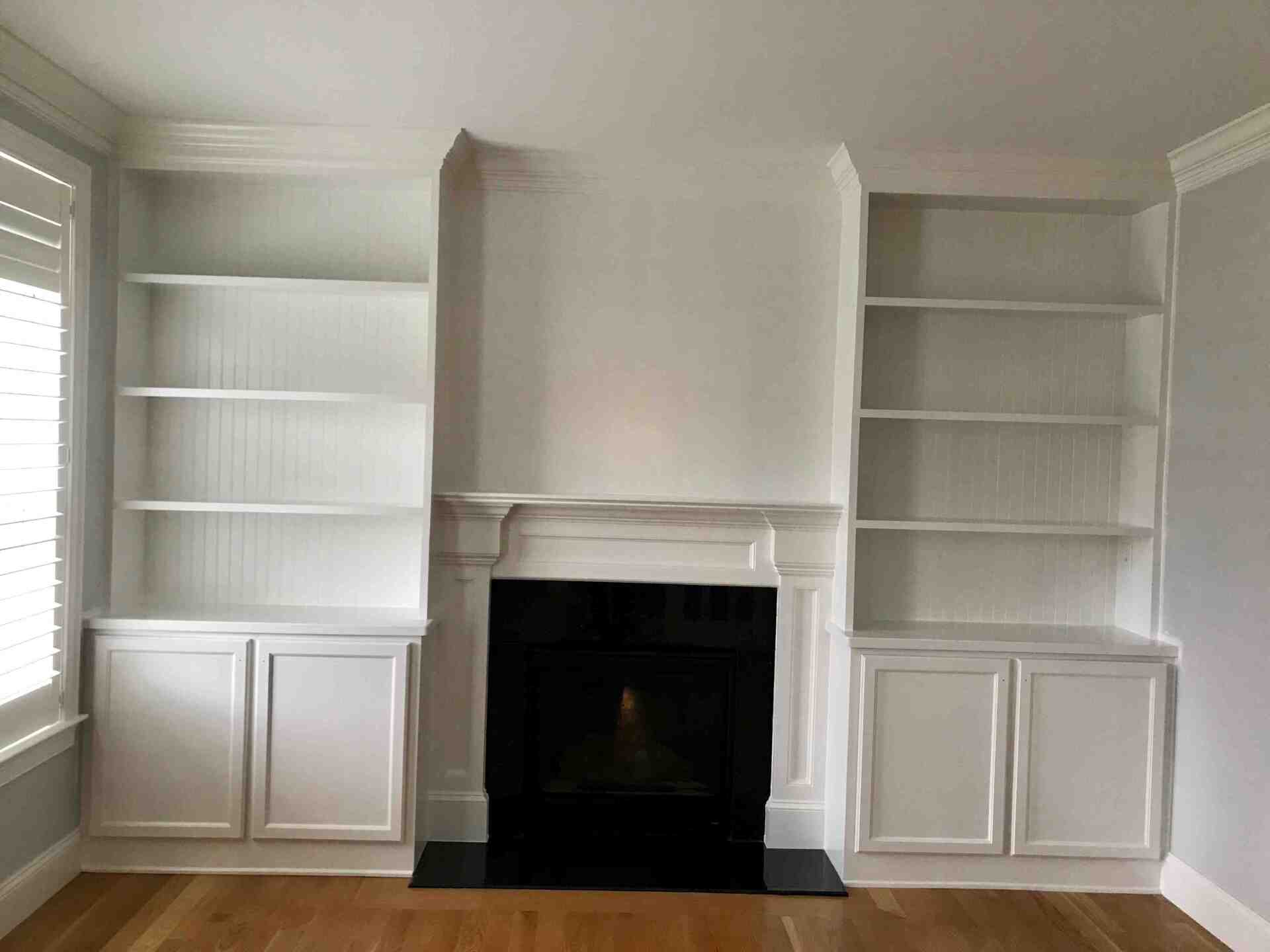 A living room with a fireplace and white shelves.