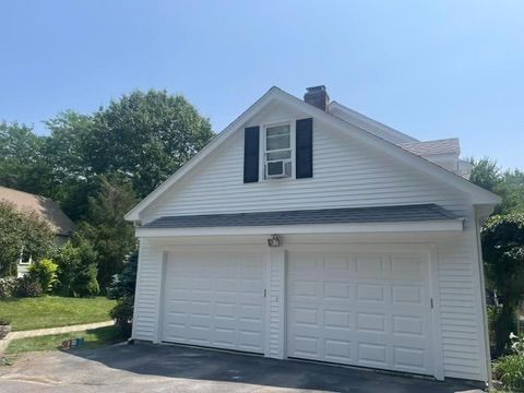 A white garage with black shutters and a blue sky in the background.