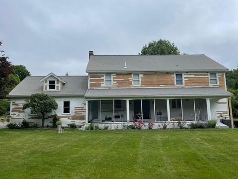 A large house with a porch and a large lawn in front of it.