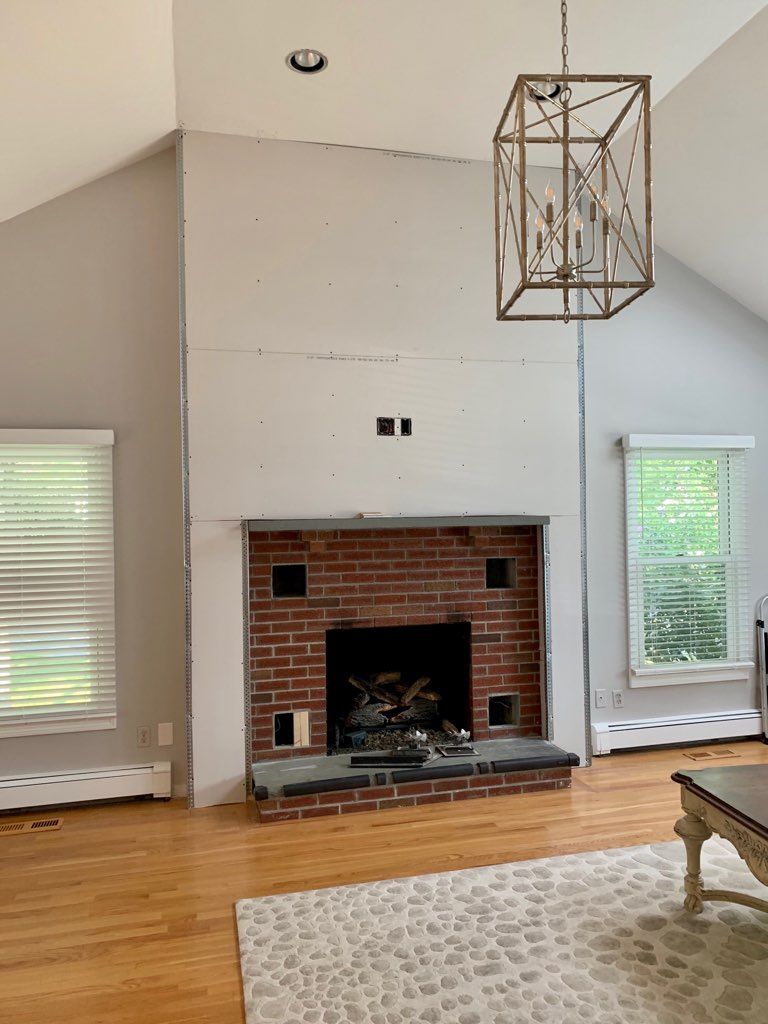 A living room with a brick fireplace and a chandelier hanging from the ceiling.
