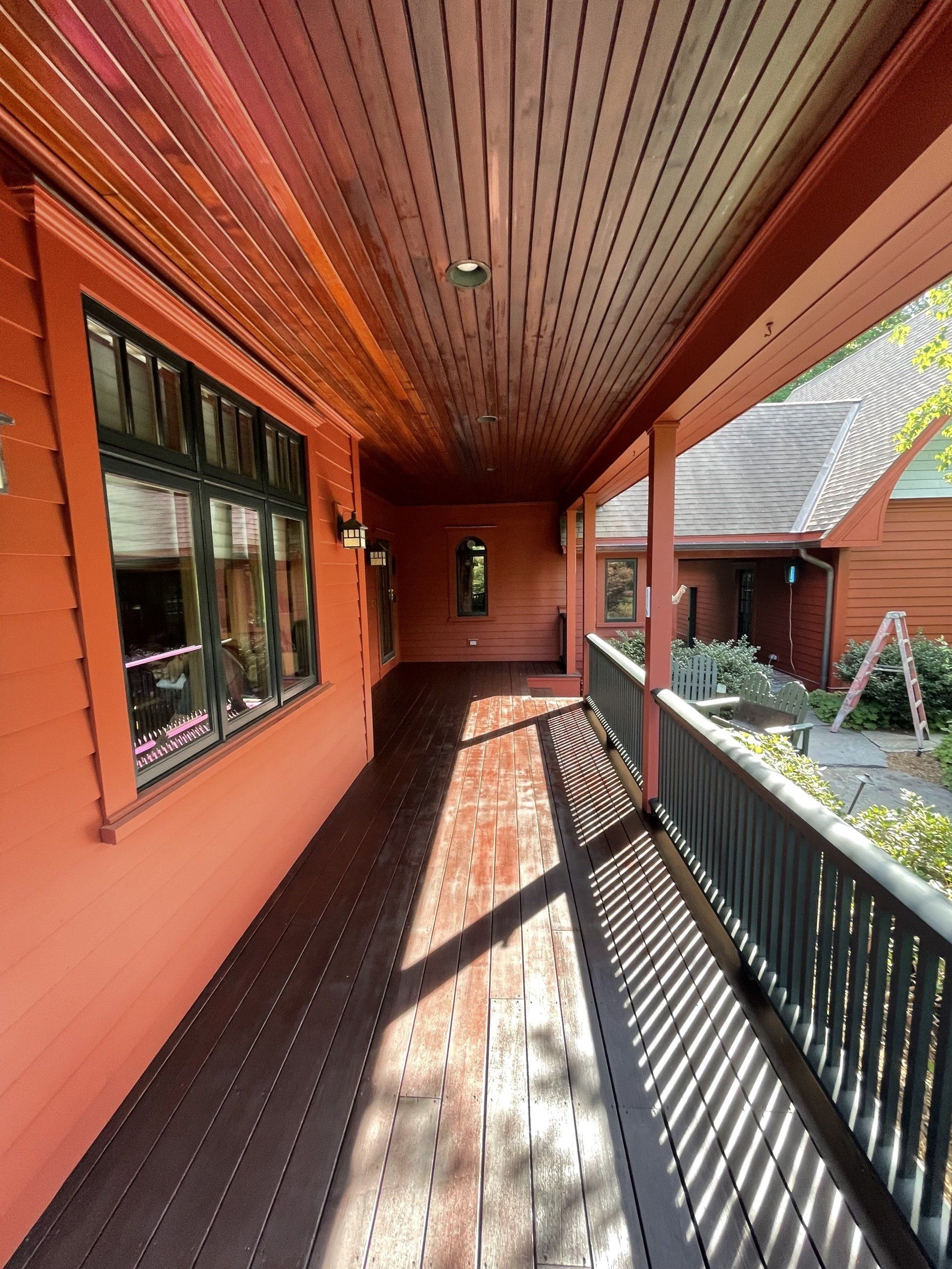 A long wooden walkway leading to a house with a balcony recently repainted