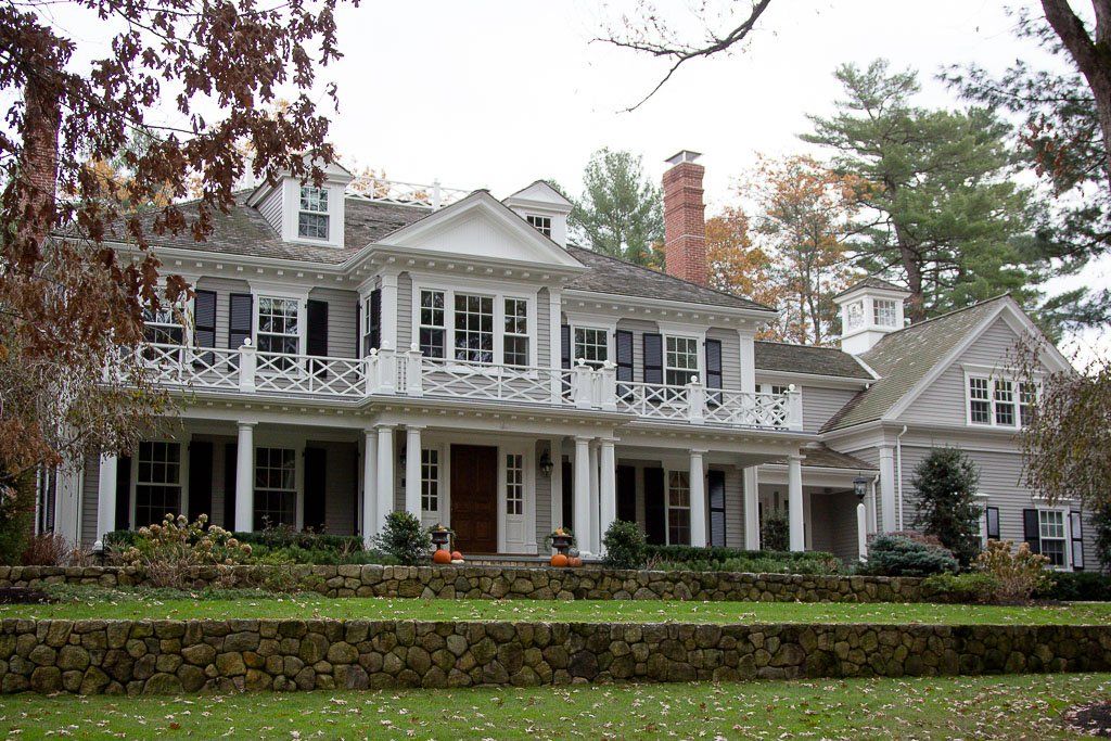 A large white house with a stone wall in front of it
