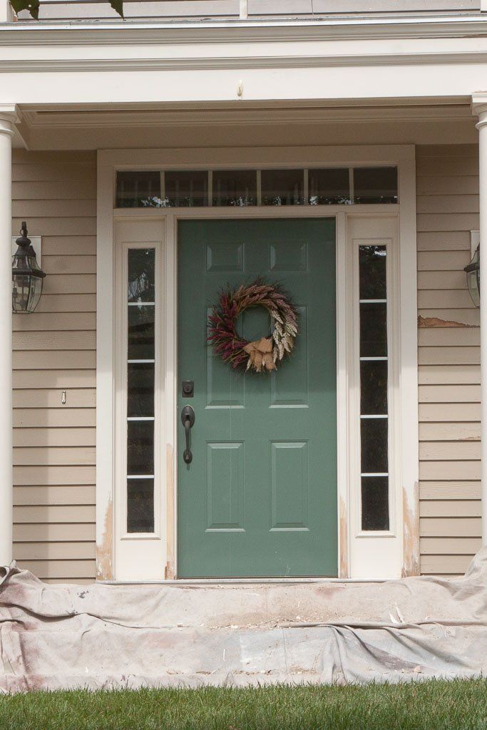 A green front door with a wreath on it
