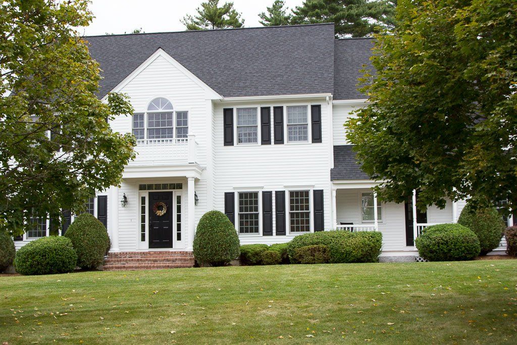 A large white house with black shutters and a black door