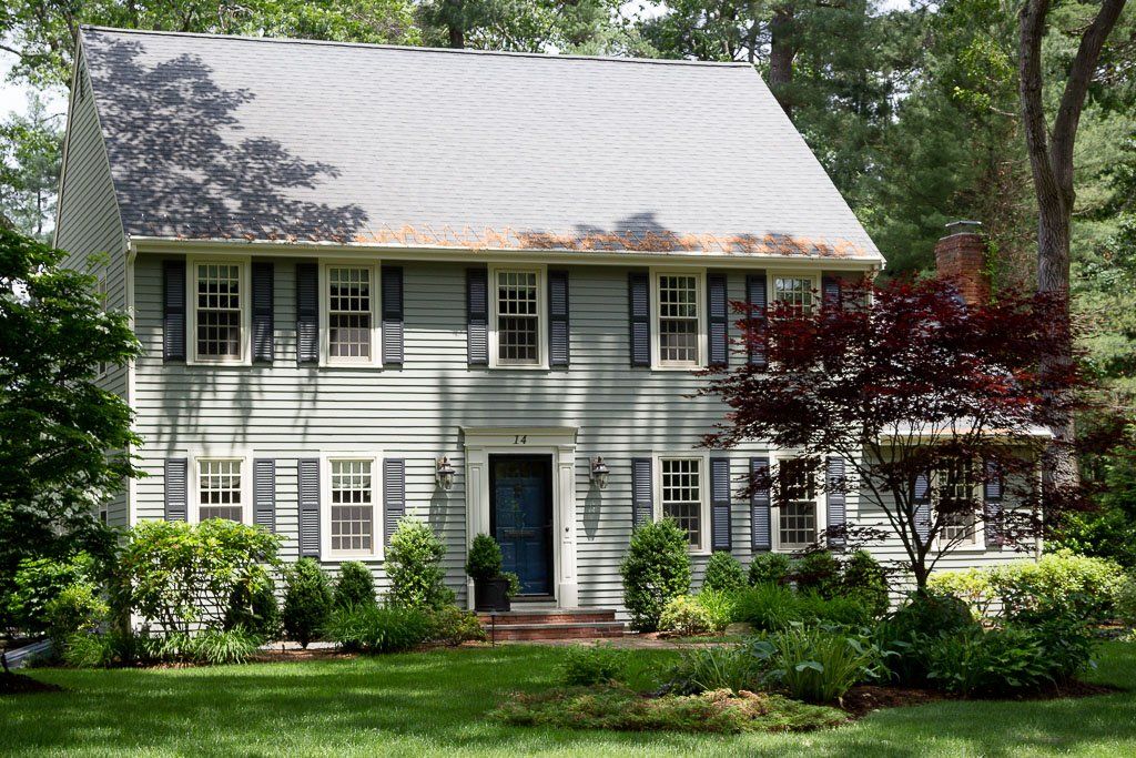 A large house with a gray roof and black shutters