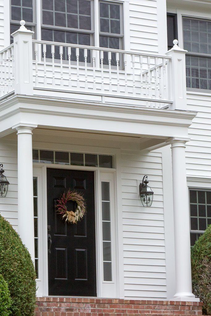 A white house with a black door and a wreath on it