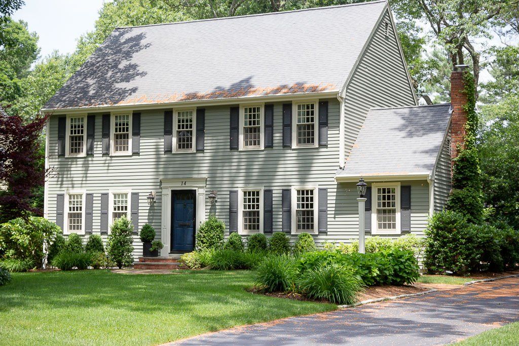 A white house with black shutters and a blue door