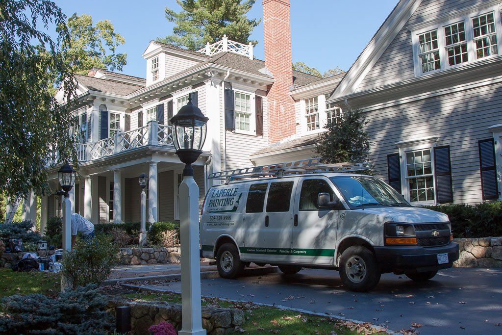 A white van is parked in front of a large house