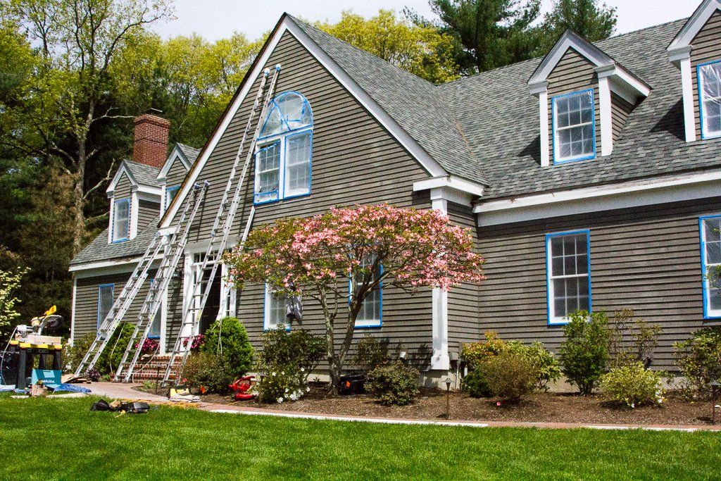 A large house with blue windows is being painted