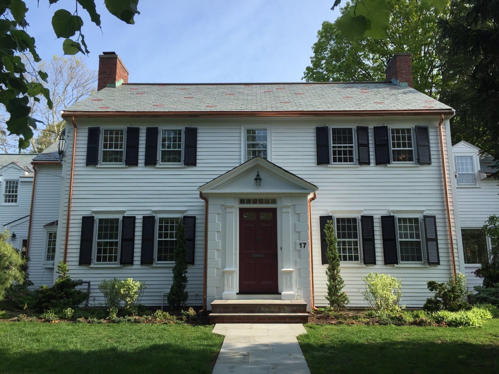A white house with black shutters and a red door