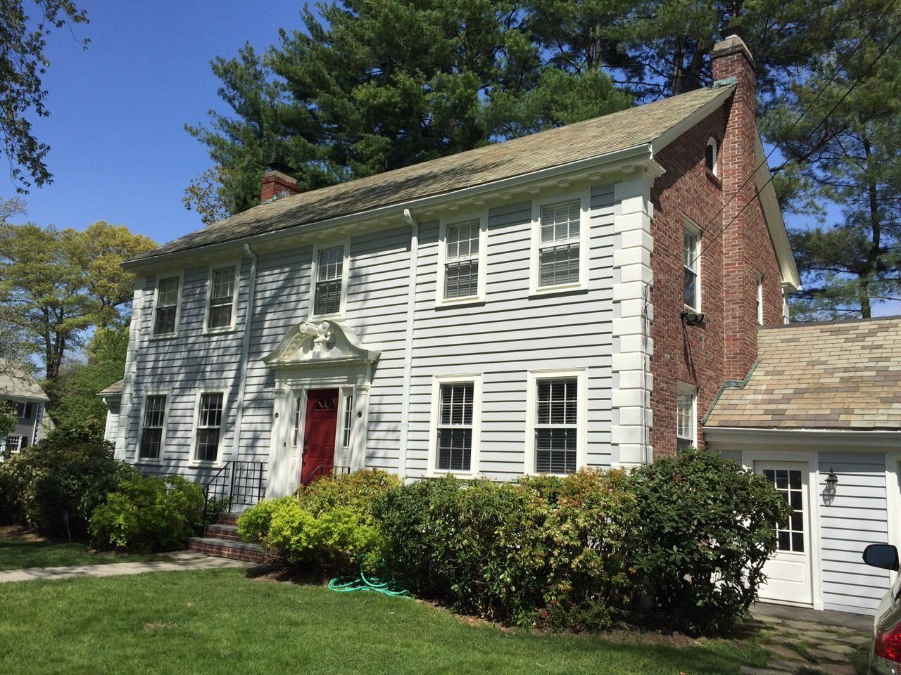 A large white house with a red door is sitting on top of a lush green lawn.