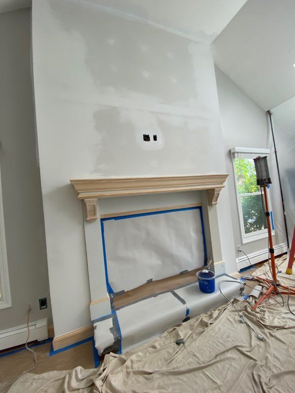 A fireplace is being painted in a living room.