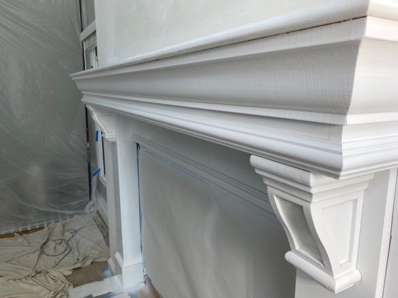 A white fireplace mantle is being painted in a room