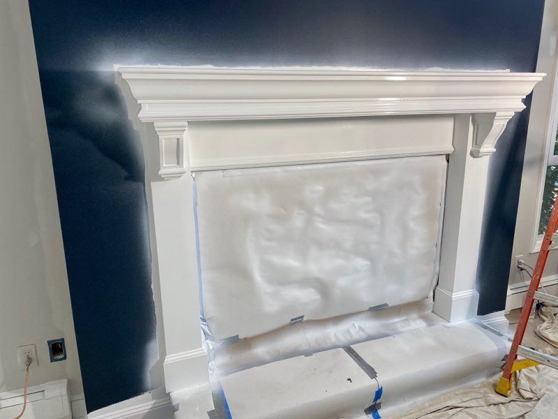 A fireplace is being painted white in a living room.